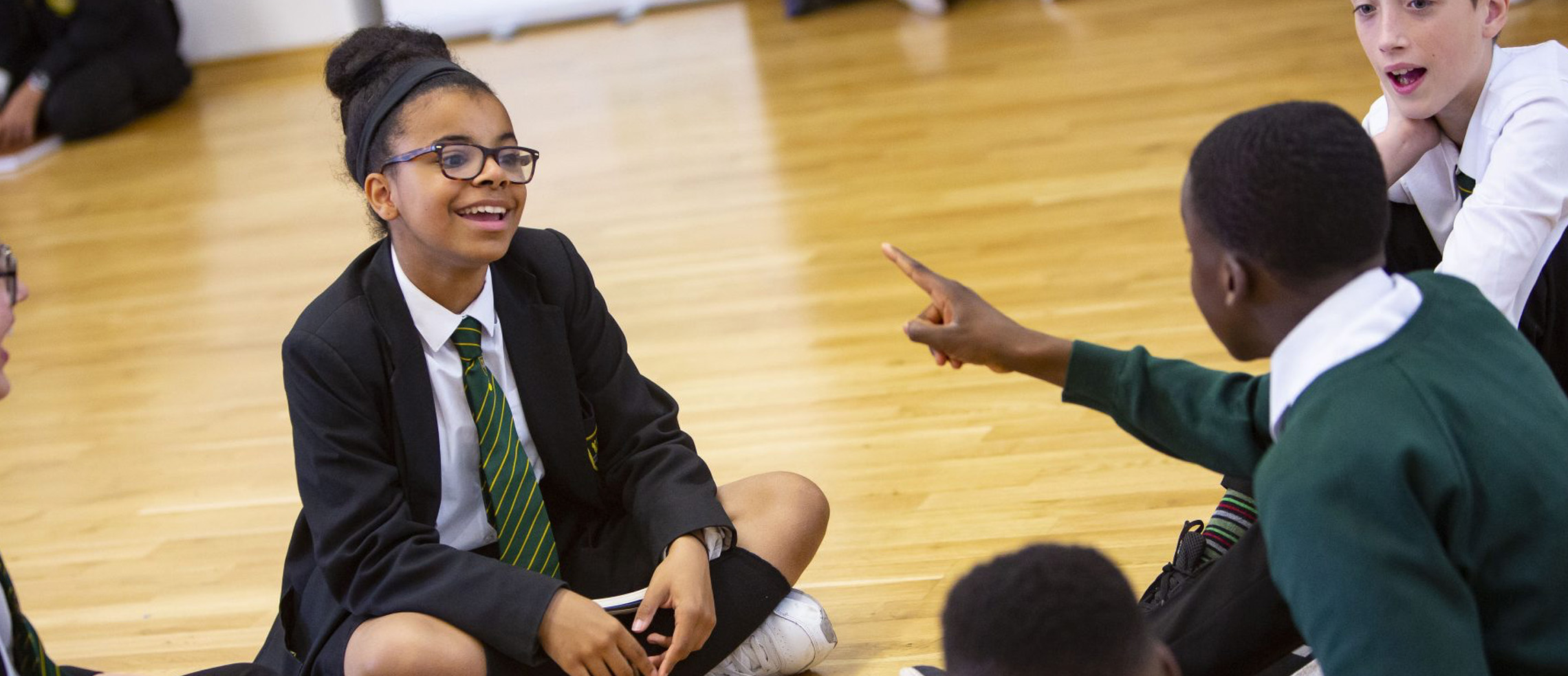 Two pupils laughing together whilst sat on the floor during a group activity
