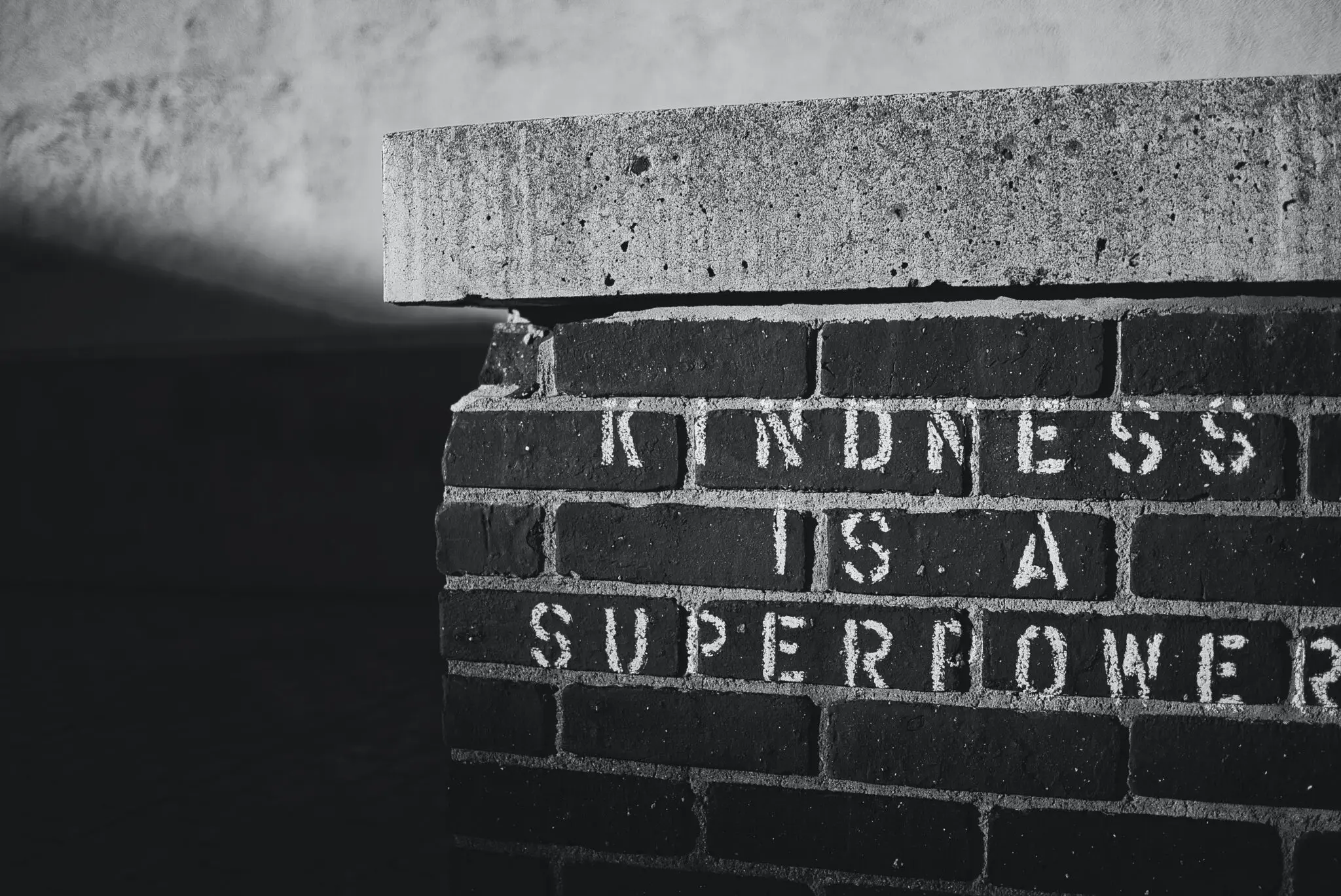 The phrase 'Kindness is a Superpower' is painted onto a brick wall.